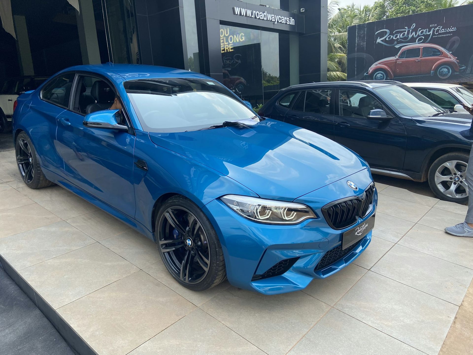 Blauer Sportwagen vor einem Autohaus
